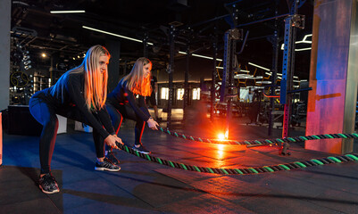 Obraz na płótnie Canvas Fit lifestyle lady working out in the gym. Young strong pretty woman training hard in modern gym.
