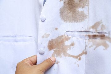 Hand show dirty sauce stain on white shirt from eating in home of daily life activity. dirty stains for cleaning concept.