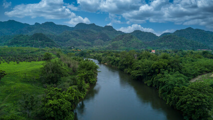 Fototapeta na wymiar Aerial view landscape with mountains, forest and a river beautiful scenery, Tree lined foliage on both sides of the river flowing through the rural countryside and hills.