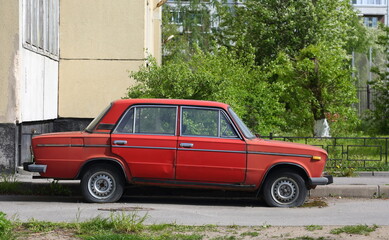 Obraz na płótnie Canvas An old red Soviet car in the courtyard of a residential building, Voroshilov Street, St. Petersburg, Russia, May 2022