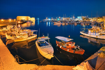 Venetian Fort castle in Heraklion and moored Greek fishing boats in port, Crete Island, Greece in...