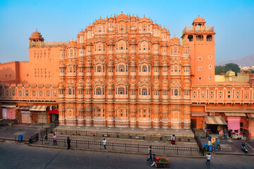 Famous landmak pink Hawa Mahal Palace of winds with people, road traffic and city transport. Mughal...