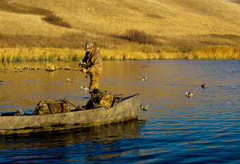 A waterfowl hunter setting decoys in the shallows 