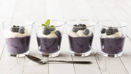 Healthy blueberry chia pudding parfaits in. a row with a spoon in front.