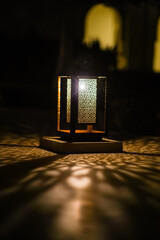Moroccan lamp illuminating different colored patterns of light on wall at night time..