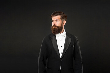 serious man in tuxedo bow tie looking aside. bride groom in formalwear on black background.