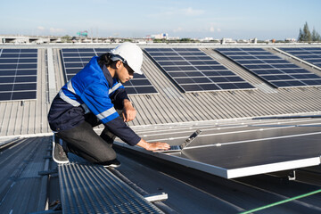 Asian technician installing inspection or repair solar cell panels on background field of...