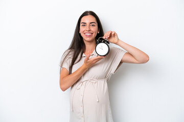Fototapeta premium Young caucasian woman isolated on white background pregnant and holding clock