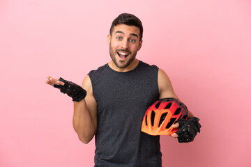 Young cyclist man isolated on pink background with shocked facial expression - obrazy, fototapety, plakaty