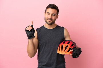 Young cyclist man isolated on pink background showing and lifting a finger in sign of the best - obrazy, fototapety, plakaty