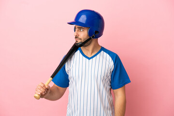 Baseball player with helmet and bat isolated on pink background looking to the side