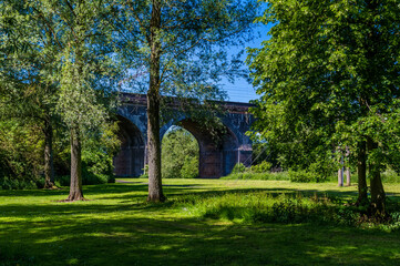 A view through trees towards the fourteen arches viaduct at Wolverton, UK in summertime