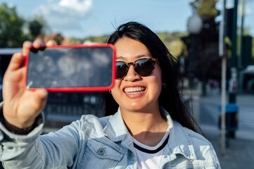 Asian woman with sunglasses taking a selfie with the phone in the city