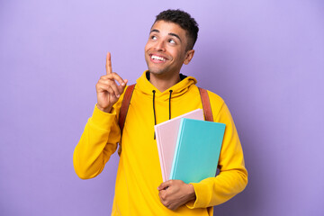 Young student Brazilian man isolated on purple background pointing up a great idea - obrazy, fototapety, plakaty