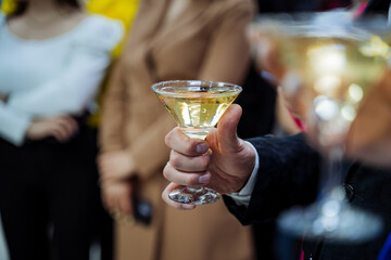 A man's hand holds a glass of champagne, an alcohol party, drink a martini from a glass.