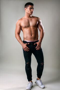 Portrait of a beautiful man guy brunet in the studio with nude torse, big strongman, sport street style, muscle male