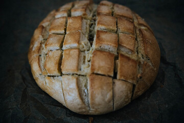 Hogaza de pan rústica sobre papel y bandeja de horno.