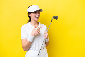 young caucasian woman playing golf isolated on yellow background pointing finger to the side and presenting a product