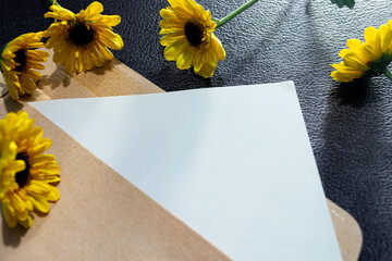 Paper and envelope on wooden surface with sunflowers flat lay with copy space.