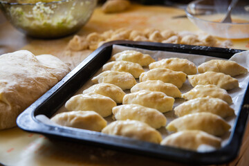 Homemade pies on a baking sheet before cooking in the oven © Anna Tkach