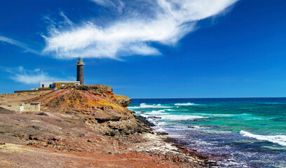 Beautiful wild rough coastal landscape, lighthouse on steep cliff, jagged rocks, ocean waves - Faro...
