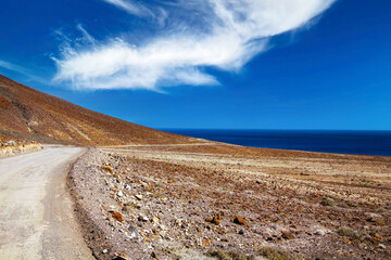 Beautiful coastal seaside dirt road, dry arid landscape, blue atlantic ocean - Road trip to Punta de Jandia, Fuerteventura