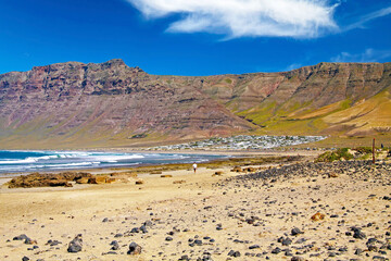 Beautiful wild rough lagoon, secluded white village located at the bottom of a rock face, sand beach, ocean waves  - Playa de Sotavento Jandia, Risco del Paso, Fuerteventura