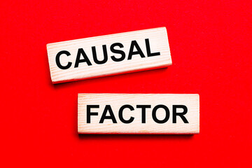 On a bright red background, there are two light wooden blocks with the text CAUSAL FACTOR