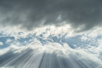 Fototapeta premium Dark clouds of thunderstorm rain clouds with a gap where the sun shines and the sun's light rays are viewed from below as a background with green tinting.