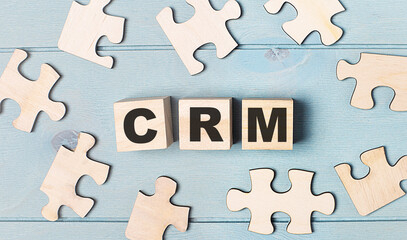 Obraz premium Blank puzzles and wooden cubes with the text CRM Customer Relationship lie on a light blue background.