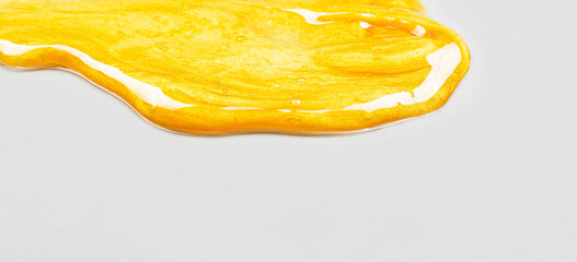 Transparent yellow smear of face cream or golden honey on a gray background. Golden creamy texture on a gray background.