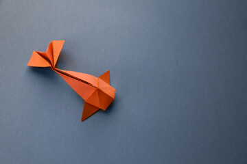Orange paper fish origami isolated on a grey background