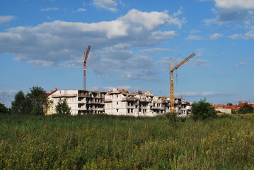 construction of apartment blocks, cranes, thickets, sunny