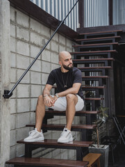 A young man in t-shirt and shorts on the stairs at city streets