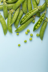 Fresh green peas on blue background. Flat lay. Top view