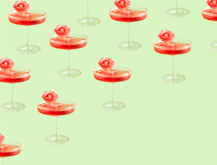 Elegant cocktail glasses, creative summer party floral pattern against pastel green background. 