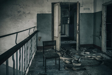 Scary room in an abandoned house. Old chair. Shabby walls. Broken door. Dirty floor.