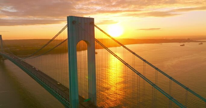 Bright huge sun reflecting in the East River. Beautiful Bronx-Whitestone bridge against sun setting over the city.
