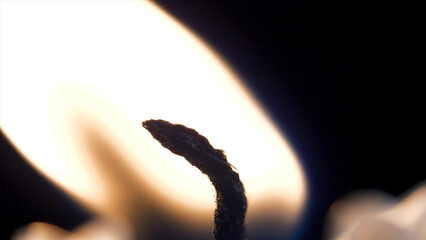 Candle flame closeup over black - Christmas. Candle is lit on a black background closeup. Brightly...