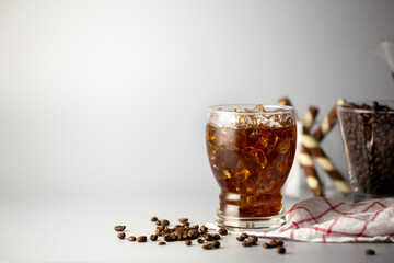 Iced americano coffee with coffee beans on grey background, Glass of black coffee, Beverage at...