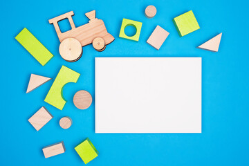 Wooden cubes and a toy train on a blue background. Copy space. Flat lay