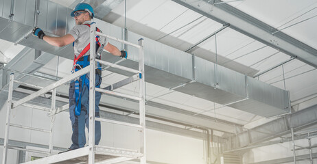 Professional HVAC Worker on a Scaffolding Installing Air Duct
