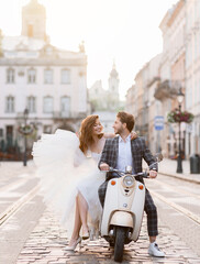 Bride couple posing on vintage scooter on street of ancient city