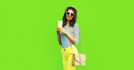 Portrait of happy smiling stylish young woman with coffee cup wearing handbag, striped t-shirt and summer straw round hat on green background, blank copy space for advertising text