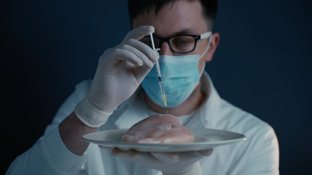 Male nutrition expert testing food products in laboratory. Lab assistant testing GMO chicken. Putting sample of chemical with injection in to test chicken meat. Genetically modified food, syringe.