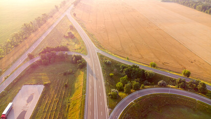 Aerial drone view flight over car interchange between agricultural wheat fields in early summer...