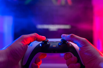 Gamepad in the hands of a gamer on a technological background. Neon lighting. Close-up. Digital...