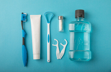 Toothbrush, tongue cleaner, floss, toothpaste tube and mouthwash on blue background with copy space. Flat lay. Dental hygiene. Oral care kit. Dentist concept. - obrazy, fototapety, plakaty