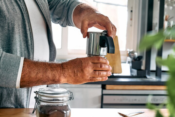 Man preparing classic Italian coffee in the mocha in the kitchen. Coffee brake. Morning habit.