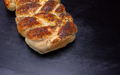 Bakery products, wicker buns with poppy seeds on a black wooden background with space for text. Cooking concept.